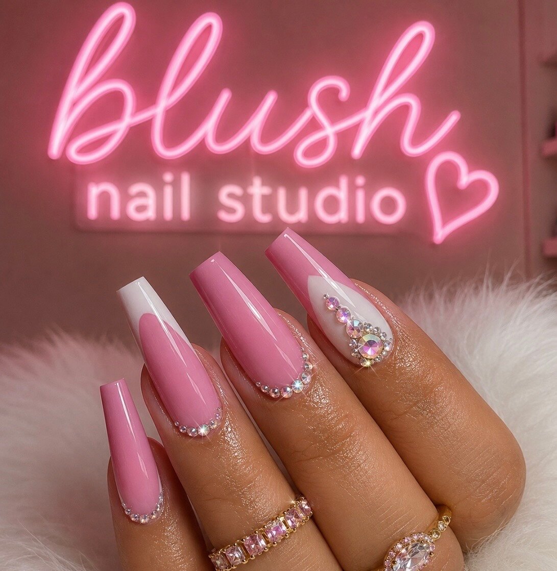 Pink coffin nails with crystal accents beneath the Blush Nail Studio neon sign