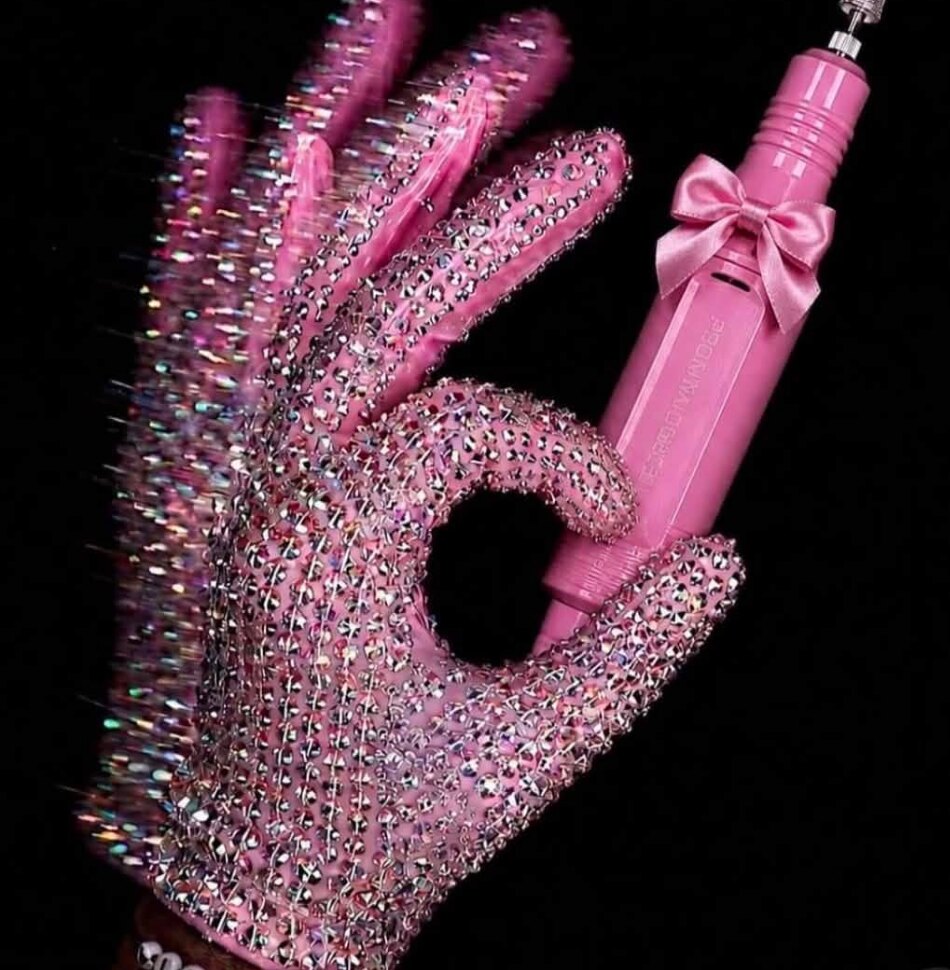 Crystal-covered glove holding a pink nail drill